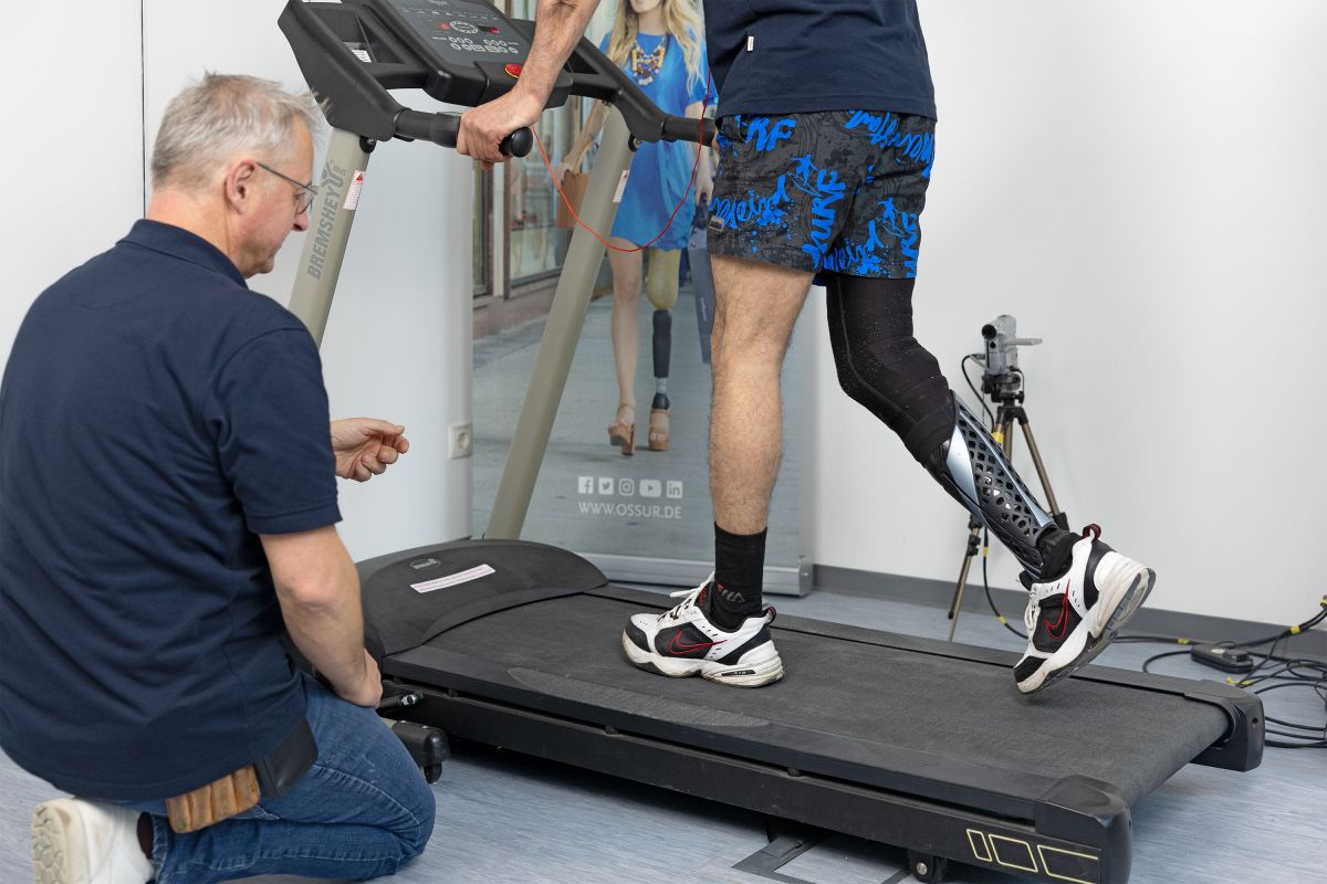 Prothesenträger läuft auf einem Laufband, der Mitarbeiter beobachtet das Laufverhalten