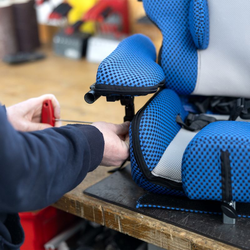 Mitarbeiter passt die Größe eines blauen Sitzes an