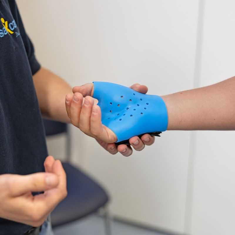 Hellblaue Handorthese wird an Hand befestigt