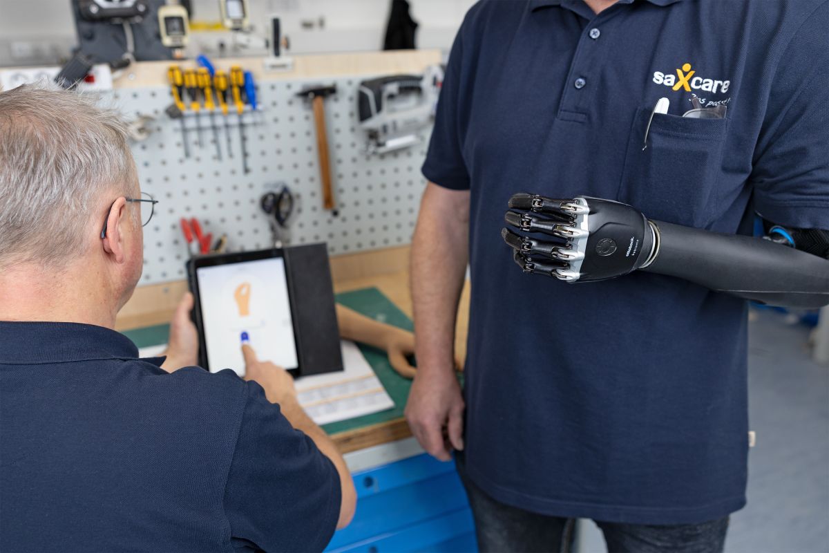 Mitarbeiter erklärt an einem Tablet die verschiedenen Einstellungen der Armprothese
