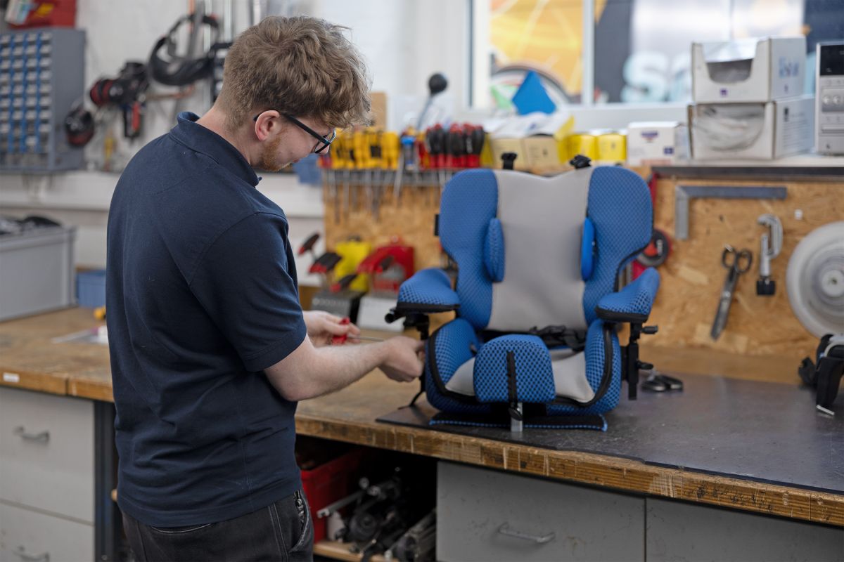 Mitarbeiter arbeitet an einer Sitzschale die auf einer Werkbank steht
